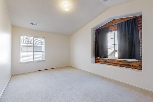 spare room featuring carpet floors and vaulted ceiling