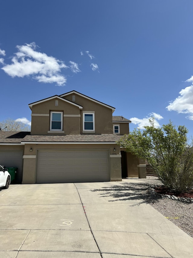 traditional home with an attached garage, concrete driveway, and stucco siding
