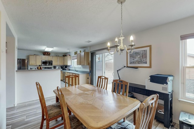dining space featuring a notable chandelier, light wood-style floors, and a healthy amount of sunlight