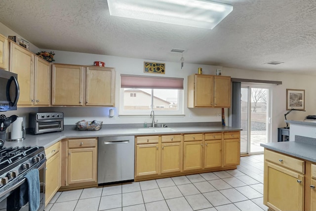 kitchen featuring stainless steel appliances, light tile patterned floors, a textured ceiling, and a sink