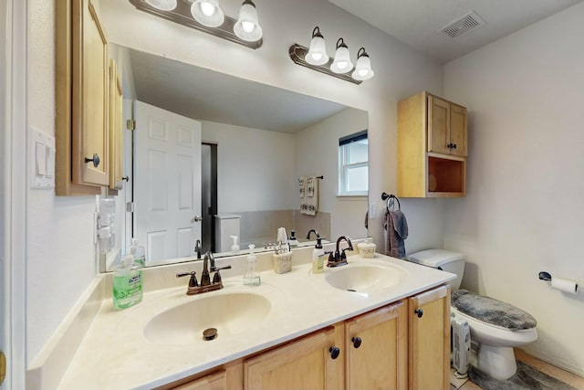 full bath with a sink, visible vents, toilet, and double vanity
