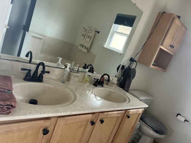 full bathroom featuring toilet, double vanity, and a sink