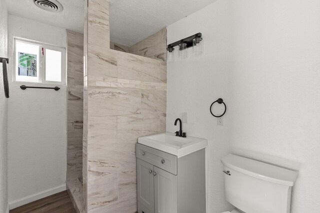 bathroom with vanity, a shower, toilet, a textured ceiling, and wood-type flooring