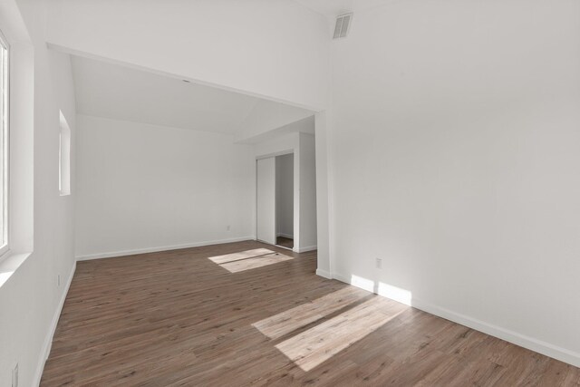 unfurnished room with dark hardwood / wood-style floors and lofted ceiling