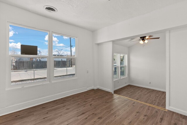 unfurnished room featuring ceiling fan, dark hardwood / wood-style flooring, a textured ceiling, and a wealth of natural light