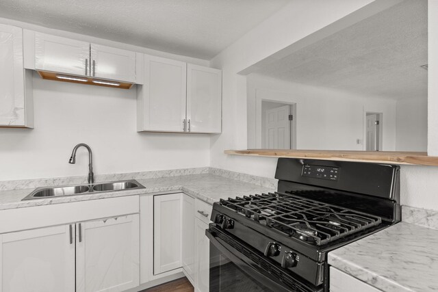 kitchen with sink, black range with gas cooktop, wood-type flooring, a textured ceiling, and white cabinets