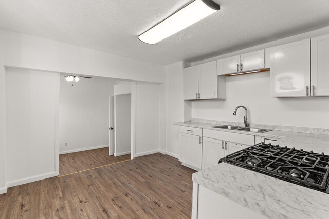 kitchen featuring white cabinetry, sink, dark wood-type flooring, gas stovetop, and a textured ceiling