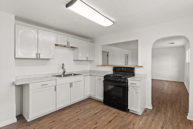 kitchen featuring white cabinets, black gas range oven, dark hardwood / wood-style flooring, and sink