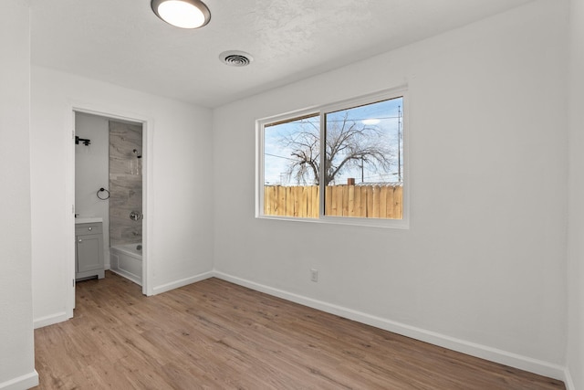 unfurnished bedroom with connected bathroom and light hardwood / wood-style flooring