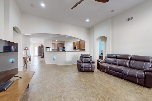 tiled living room featuring ceiling fan and a high ceiling