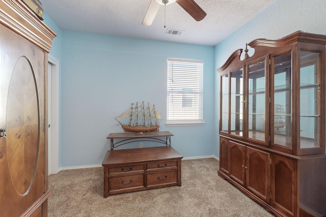 interior space featuring ceiling fan, light colored carpet, and a textured ceiling