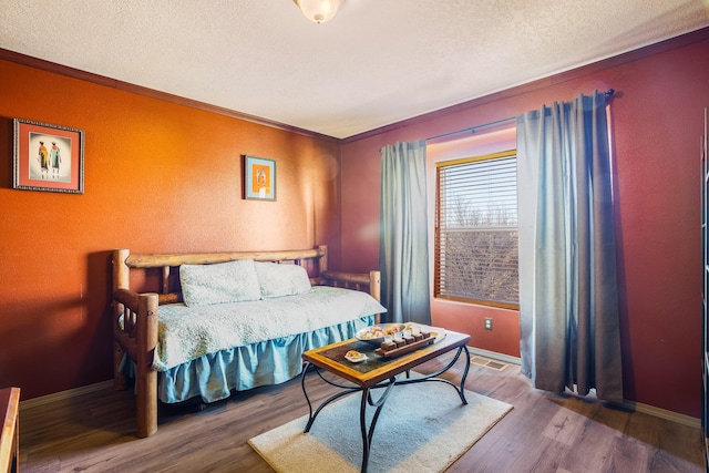 bedroom featuring a textured ceiling, wood-type flooring, and crown molding