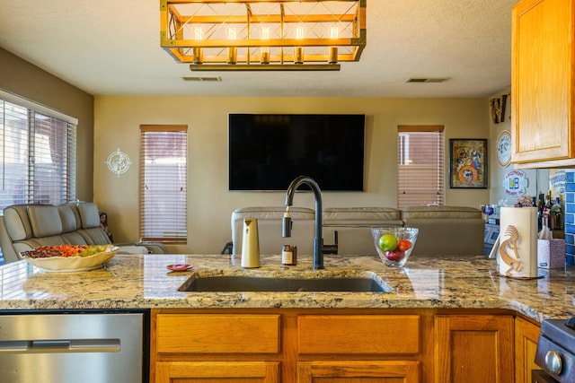 kitchen with kitchen peninsula, light stone counters, a textured ceiling, sink, and dishwasher