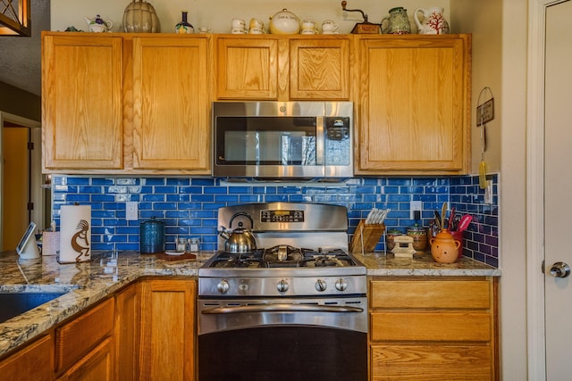 kitchen with light stone countertops, decorative backsplash, and stainless steel appliances