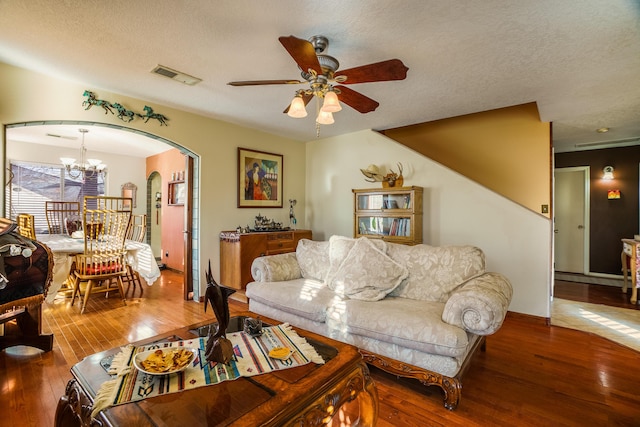 living room featuring a textured ceiling, hardwood / wood-style floors, and ceiling fan with notable chandelier