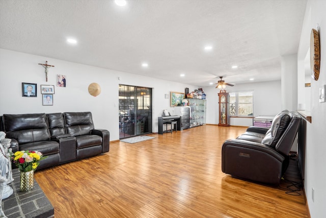 living room featuring ceiling fan, light hardwood / wood-style floors, and a textured ceiling