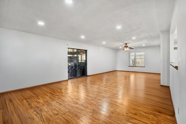 unfurnished room with ceiling fan, a healthy amount of sunlight, light wood-type flooring, and a textured ceiling