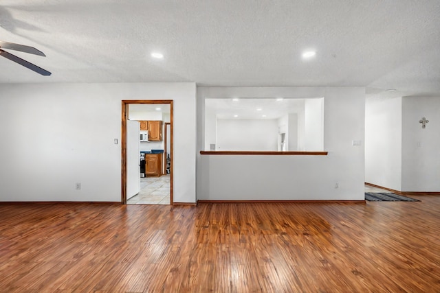 unfurnished living room featuring a textured ceiling, light hardwood / wood-style floors, and ceiling fan