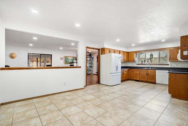 kitchen featuring a textured ceiling, white appliances, light tile patterned floors, and sink