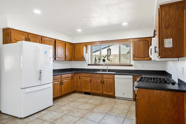 kitchen with a textured ceiling, white appliances, and sink