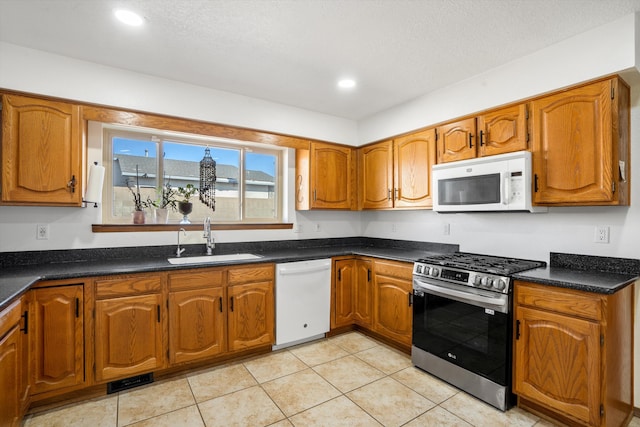 kitchen with white appliances, sink, and light tile patterned floors