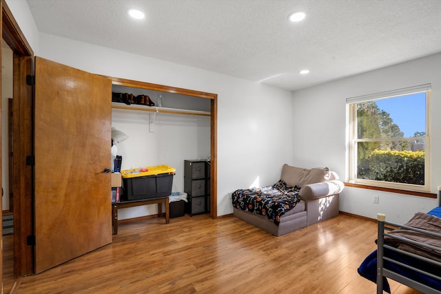 bedroom with a closet, wood-type flooring, and a textured ceiling