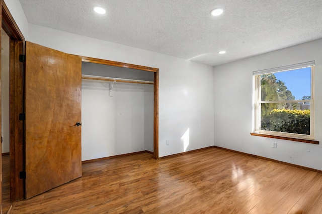 unfurnished bedroom featuring a closet, wood-type flooring, and a textured ceiling