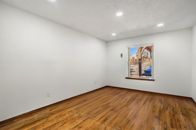 unfurnished room featuring hardwood / wood-style floors and a textured ceiling