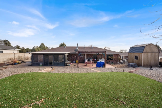 rear view of property with a storage unit, a lawn, a patio area, and a sunroom