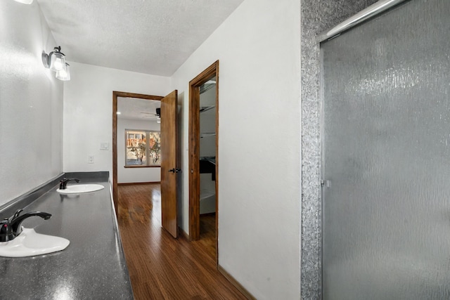 bathroom featuring hardwood / wood-style floors, vanity, ceiling fan, a textured ceiling, and a shower with shower door