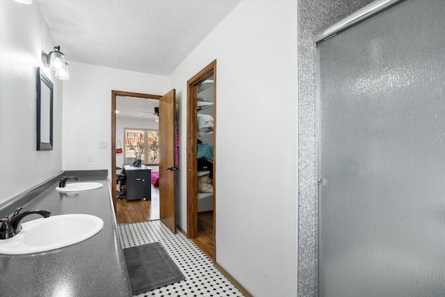 bathroom featuring a textured ceiling, ceiling fan, vanity, and an enclosed shower