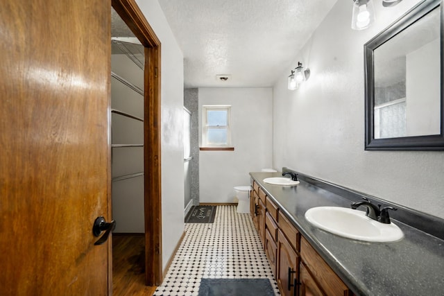 bathroom featuring vanity, toilet, and a textured ceiling