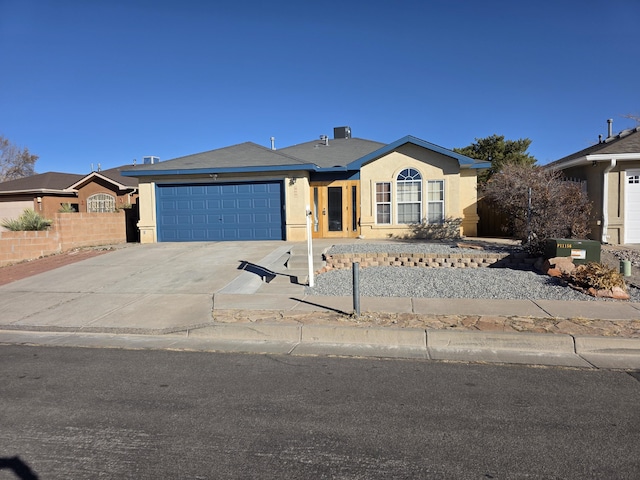 ranch-style home featuring stucco siding, an attached garage, concrete driveway, and fence