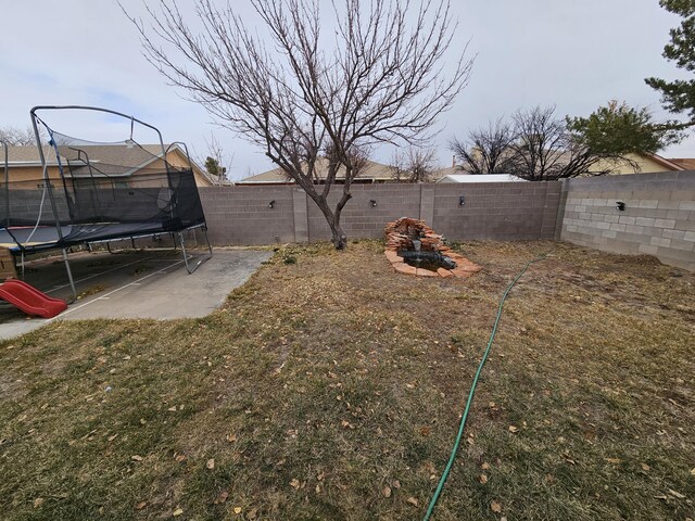 view of yard with a trampoline and a fenced backyard