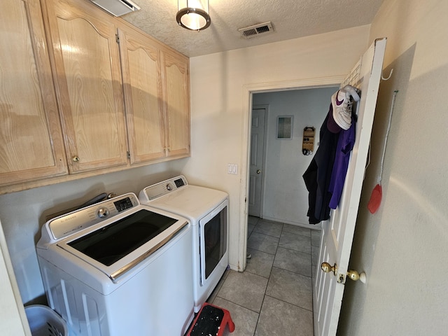 laundry room featuring visible vents, a textured ceiling, cabinet space, light tile patterned floors, and washing machine and clothes dryer