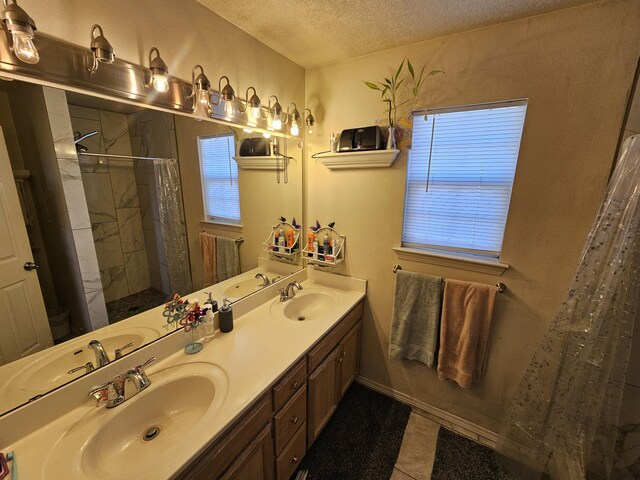 bathroom featuring a textured ceiling, a tile shower, and a sink