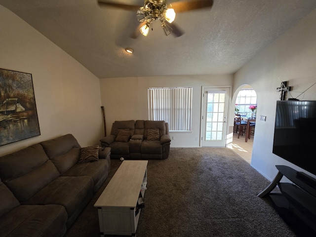 living room featuring a textured ceiling, carpet floors, arched walkways, ceiling fan, and vaulted ceiling