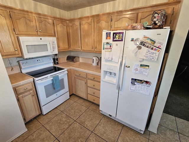 kitchen with light tile patterned flooring, white appliances, and tile counters