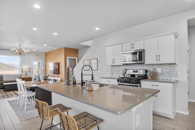 kitchen with decorative backsplash, appliances with stainless steel finishes, a breakfast bar area, and a sink