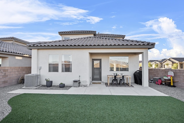 rear view of property featuring a yard, central AC unit, and fence