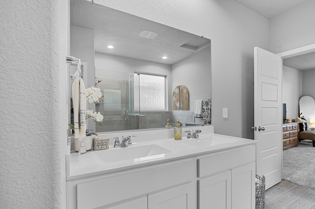 bathroom with a textured ceiling, vanity, and a shower with door