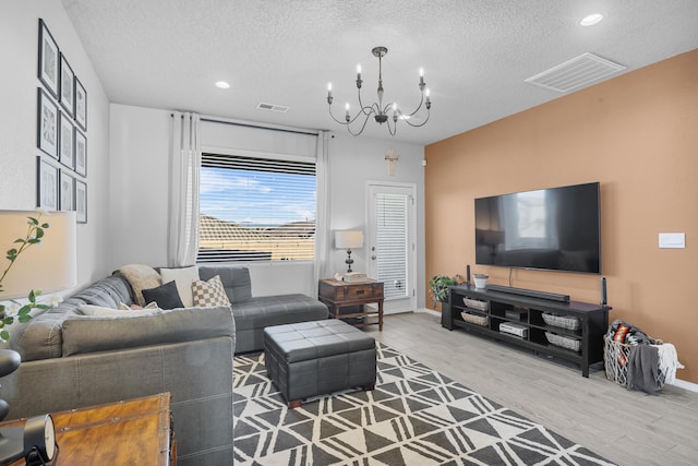 living room with an inviting chandelier, a textured ceiling, and hardwood / wood-style flooring