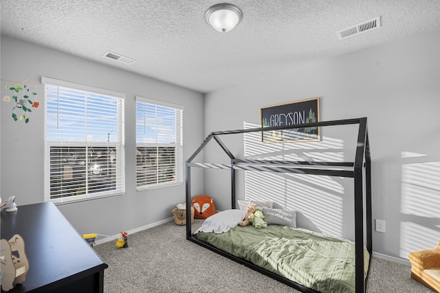 carpeted bedroom with visible vents, baseboards, and a textured ceiling