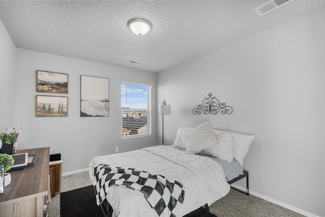 carpeted bedroom with visible vents, a textured ceiling, and baseboards