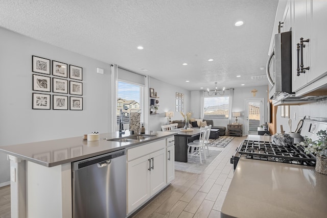 kitchen featuring white cabinetry, an island with sink, stainless steel appliances, and a textured ceiling