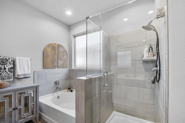 bathroom featuring a bath, recessed lighting, a stall shower, and a textured ceiling