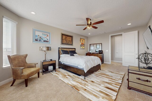 carpeted bedroom with ceiling fan and a textured ceiling