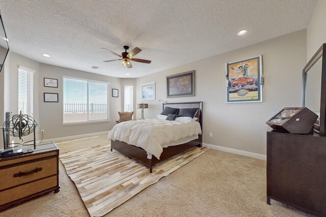 carpeted bedroom with ceiling fan and a textured ceiling