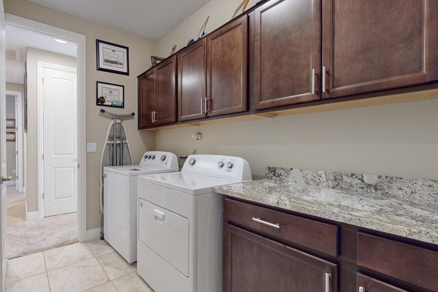 washroom with cabinets, washer and dryer, light tile patterned floors, and a textured ceiling