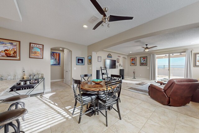 dining space featuring light tile patterned flooring, ceiling fan, and a textured ceiling